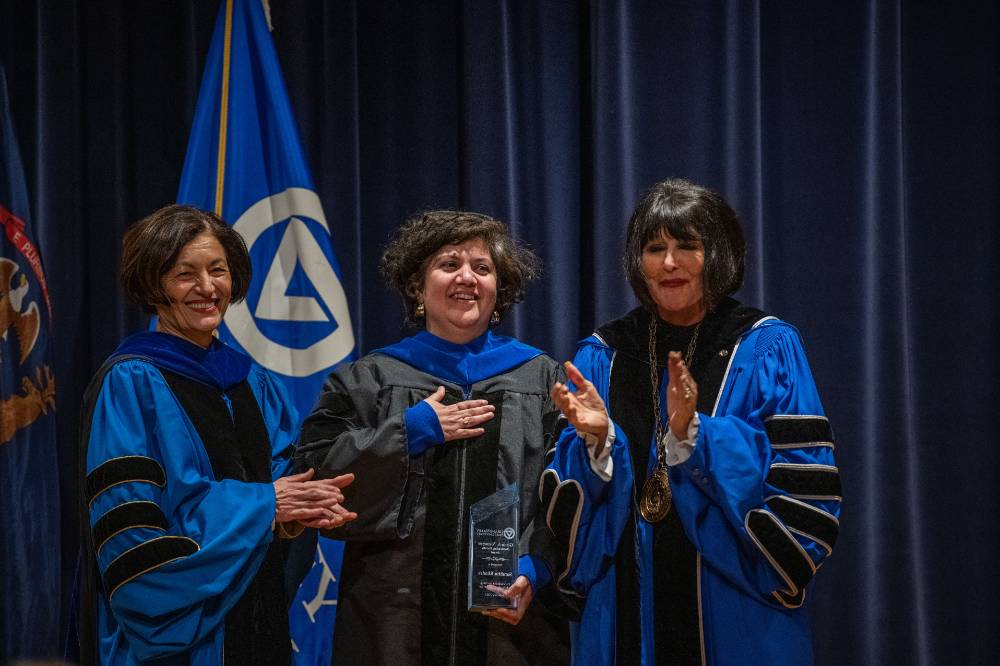 Provost Mili and President Mantella are all smiles with woman on stage